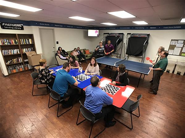 Members of a FASTSIGNS team spend time together and play games in a break room